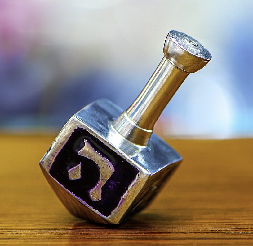 A dreidel on a table showing the letter heh