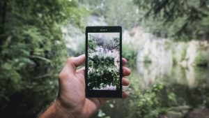 A phone showing an image of trees and nature behind it.